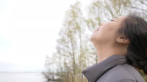 Close up face of Asian woman standing and taking a deep breath getting fresh air