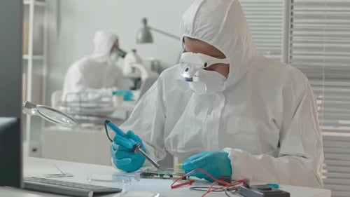 Technician Soldering Circuit Board in a Cleanroom Environment