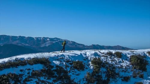 Person Walking on Snowy Mountain Ridge in Winter