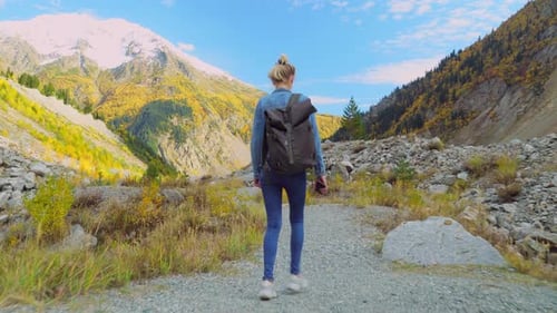 young tourist walks through mountainous area and looks at beautiful landscape.