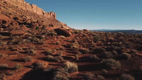Drone Flying Low Above Ground Near Massive Mountain, Sandstone Landscape Covered with Rocks and