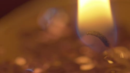 Makroansicht der goldenen Flamme einer Kerze, die die Dunkelheit erleuchtet - statisch isoliert