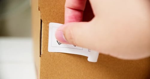 Attaching 'Made in Korea' Sticker to Brown Box