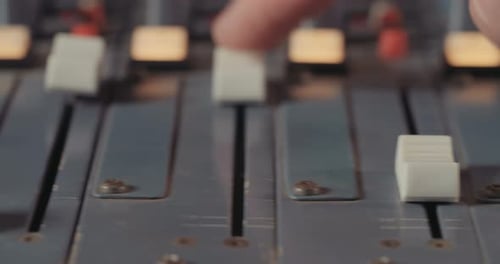 Sound engineer working in a recording studio with a sound console and microphones