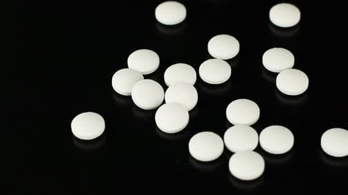 Pile of White Round Pills on Black Background
