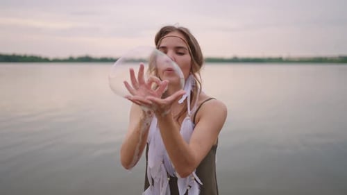 Woman Blowing Soap Bubbles by Calm Lake