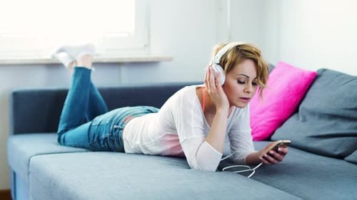 Woman Lying on Sofa Listening to Music