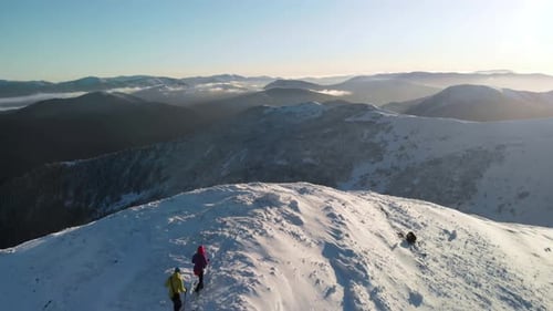 Drone Flying Over Couple of Hikers Walking Towards the Summit in Winter