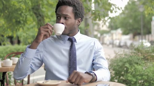 Waiting African Businessman Drinking Coffee in Outdoor Cafe and Checking Time