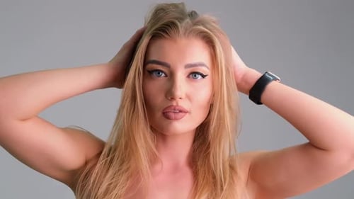 Blonde Woman Styling Hair Posing in Studio