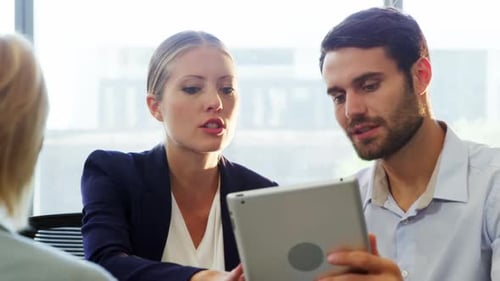 Team Discussing Tablet in Bright Office Setting