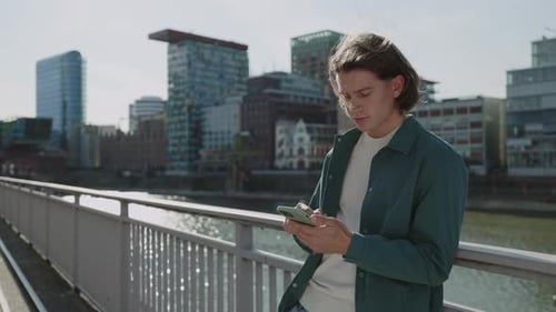 Young Guy Using Modern Smartphone Standing on Street