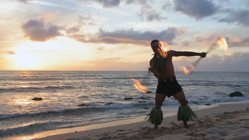 Fire juggler juggling fire sticks in the beach