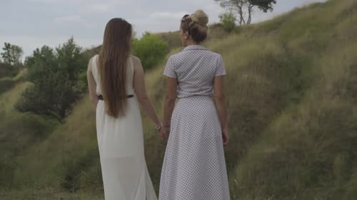Women Hold Hands and Walk in Countryside