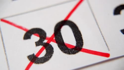 El número 30 del calendario está tachado con una cruz roja en una macro en una hoja blanca