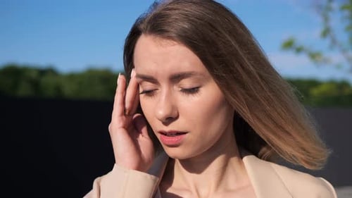 Une directrice débordée a mal à la tête debout à l'extérieur au soleil