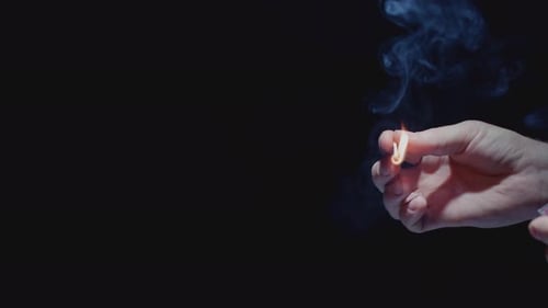 Hand Holding a Lit Match on Black
