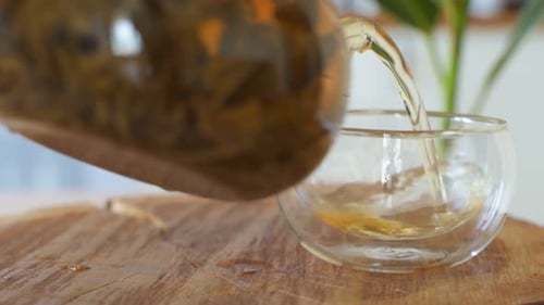 Tee-Eingießen. Tee wird in eine transparente Teetasse aus Glas gegossen. Tee-Zeit. Teekanne aus transparentem Glas und
