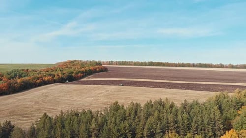 An Autumn Landscape - Field and Trees - Tractor Plows the Field
