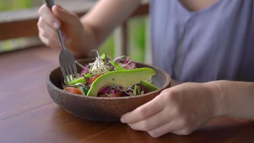 A Young Woman in a Tropical Cafe Eat Healthy Vegetarian Salad. Vegan Food Concept. Slowmotion Shot