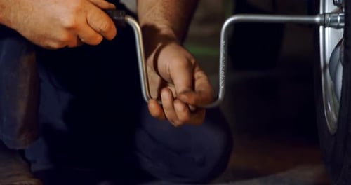Male Mechanic Fixing Car Tire with Rim Wrench 4k