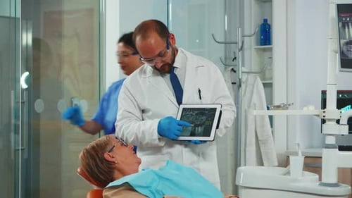 Ortodoncista usa tableta para explicar las radiografías dentales al paciente
