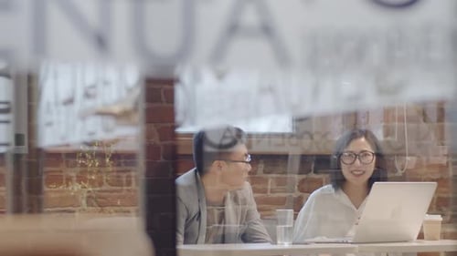 Young Adults Working Together in Cafe on Laptop