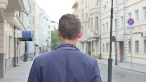 Back View of Mature Adult Man Walking in Empty Street
