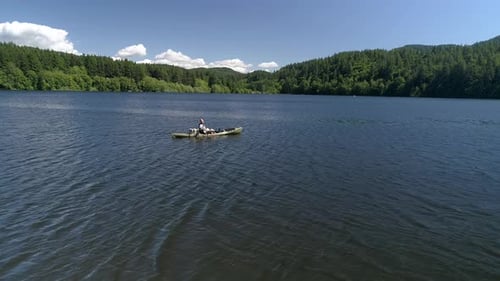 Antena de pesca en cámara lenta del hombre de lanzamiento de kayak en el lago