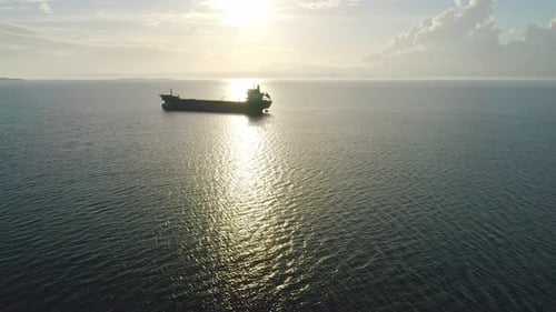 Cargo Ship Sailing on Ocean at Sunset