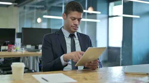 Young African Businessman Using Tablet in Modern Office