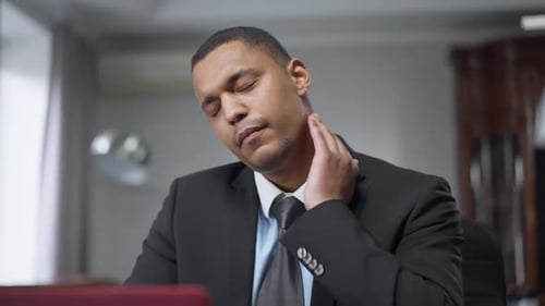 Portrait of Focused Young Man Having Sudden Neck Pain Sitting at Laptop in Home Office