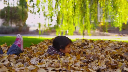 Happy Girl Jumps into Autumn Leaves Pile