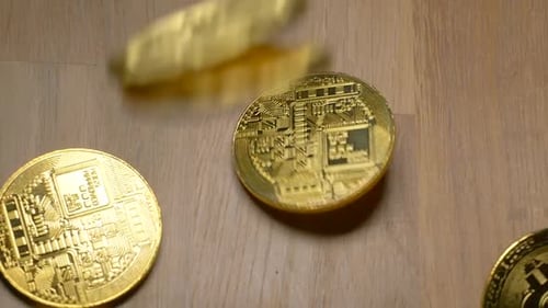 Several golden bitcoins falling in slow motion on table,close up shot
