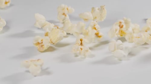 Frisches Popcorn fällt in Zeitlupe auf eine weiße Oberfläche
