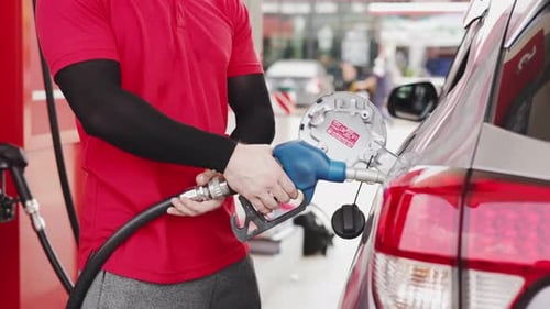 Benzin an der Tankstelle pumpen. Nahaufnahme einer Hand, die die Kraftstoffdüse hält