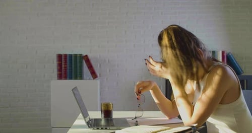 Tired Woman Working at Desk with Laptop