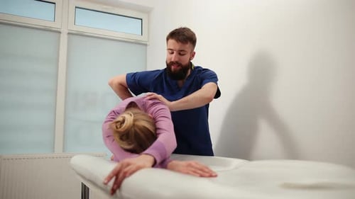 Man Adjusting Woman's Back in Doctor's Office