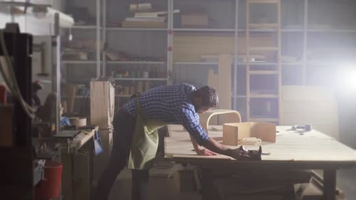 Kraftman a Man with a Beard in a Shirt in the Workshop Planes a Tree with Shavings