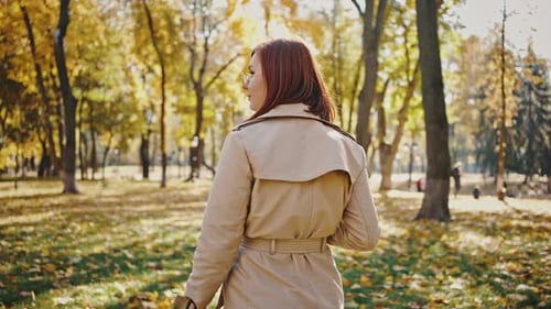 Young Female is Smiling While Walking By Autumn City Park