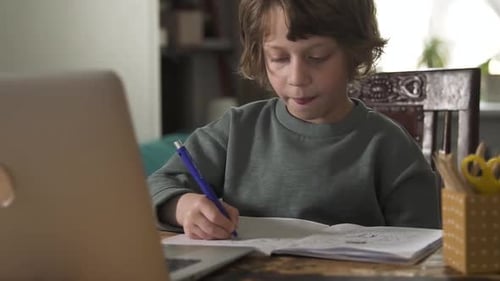 Child Drawing at Desk with Laptop in Home