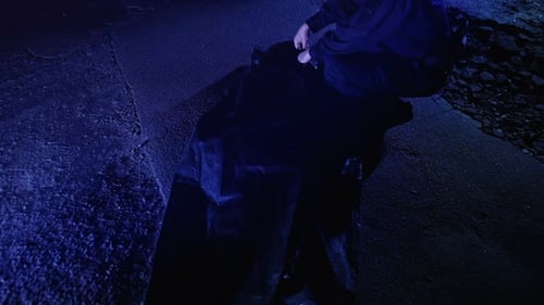 Dark Figure Opens Mysterious Bag at Night