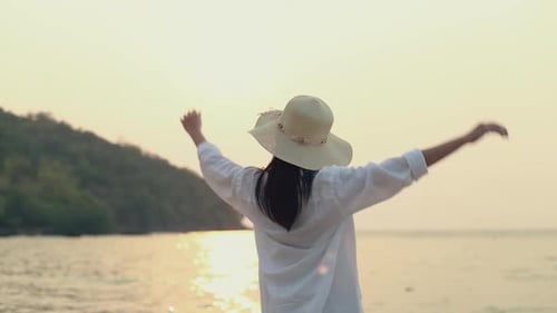 Woman in Hat Enjoying Peaceful Beach Sunset