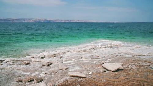 Dead Sea salt beach in Jordan, close to the Israel border. Clear blue and calm salty seaside water w