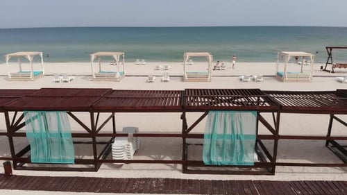 Ocean Sand Beach with Wooden Sun Loungers and Tourists