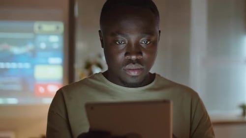 African American Man Working on Tablet in Office at Night