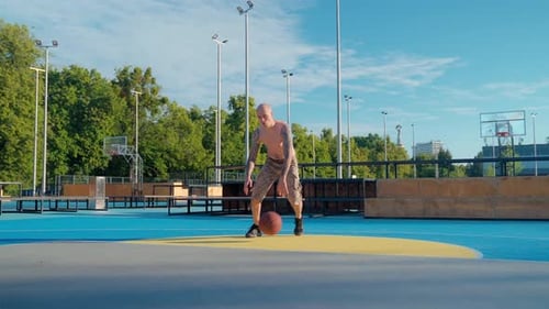 Tattooed Man Dribbling Basketball on Outdoor Court