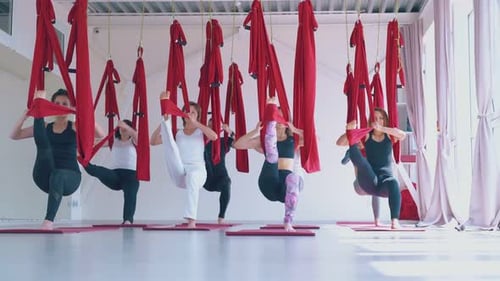 Women Practicing Aerial Yoga in a Bright Studio