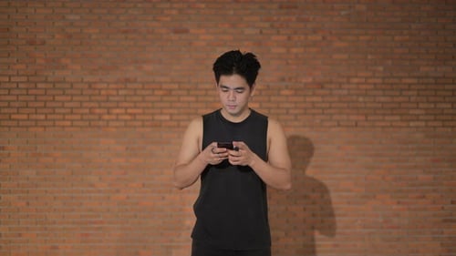 Man Using Mobile Phone Against a Brick Wall