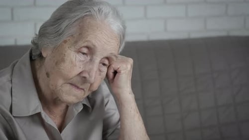 Senior Woman Sitting Indoors and Looking Down